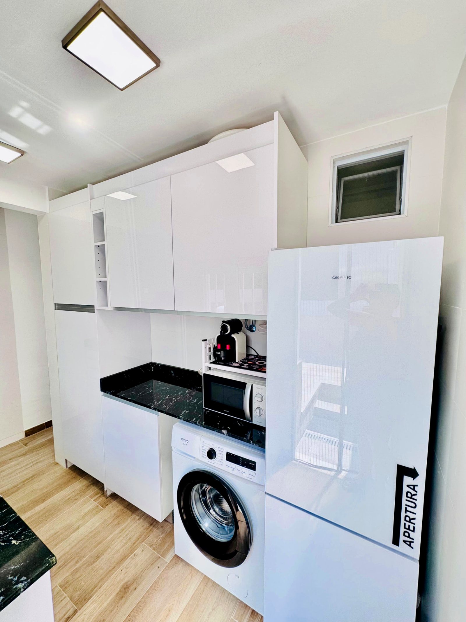 Zona de cocina con lavadora, microondas y nevera en La Cova